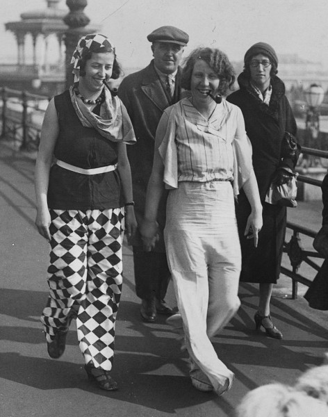 25th March 1932: Two fair followers, who caused a sensation among holiday makers at Brighton, walking along the front wearing brilliantly coloured beach pyjamas and smoking pipes. (Photo by Fox Photos/Getty Images)