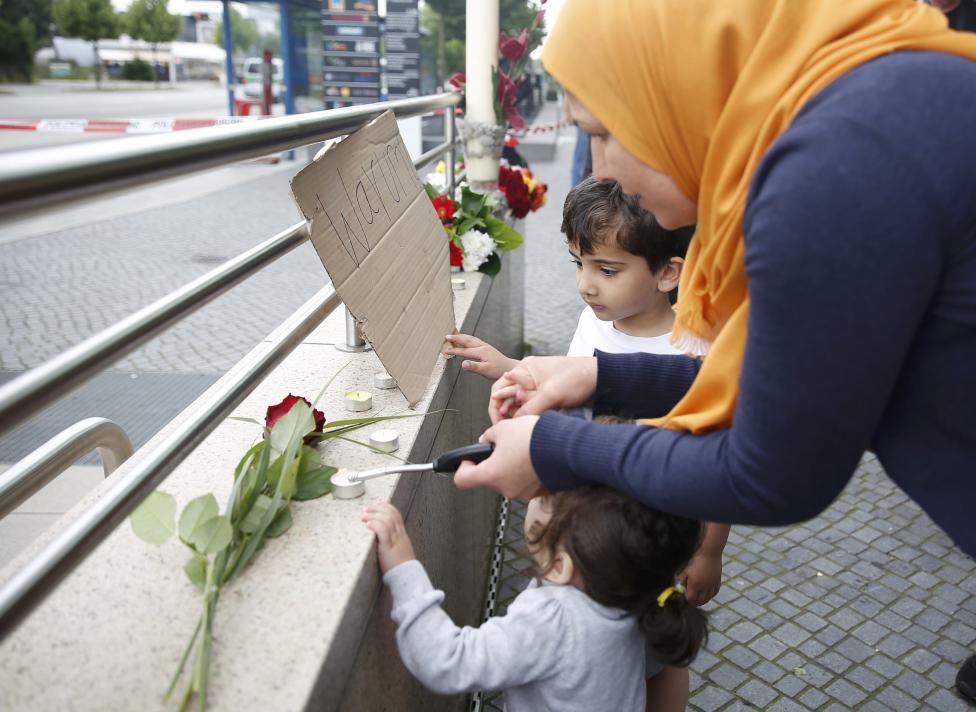 A woman lights candles on a wall near the Olympia shopping mall, where yesterday's shooting rampage started, in Munich, Germany July 23, 2016. REUTERS/Michael Dalder