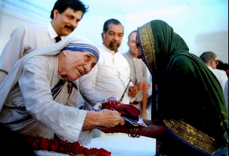 Mother Teresa presents documents for a new house to a villager from Latur in Bombay September 26, 1994. REUTERS/Savita Kirloskar/File Photo