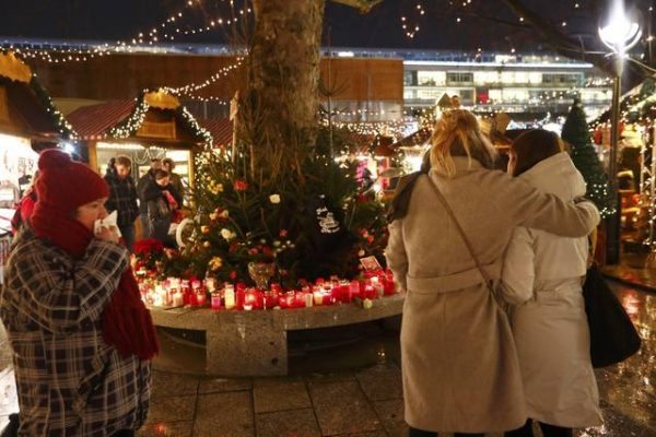 People mourn beside flowers and candles placed at the Christmas market at Breitscheid square in Berlin, Germany, December 22, 2016, following an attack by a truck which ploughed through a crowd at the market on Monday night. REUTERS/Fabrizio Bensch TPX IMAGES OF THE DAY