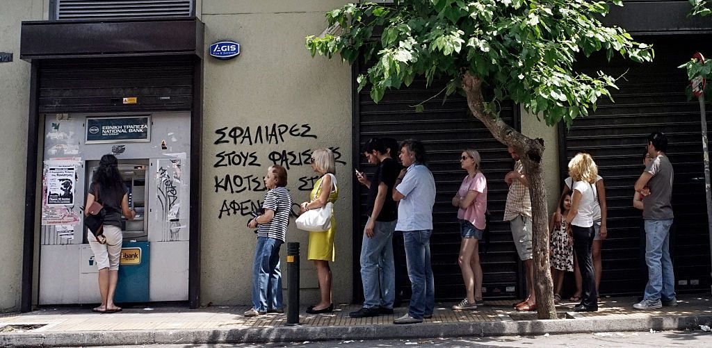 ATHENS, GREECE - JUNE 27: Greeks queue in front of the National Bank to use ATM to withdraw cash as Parliament holds an emergency session for the government's proposed referendum June 27, 2015 in Athens, Greece. Greece's fraught bailout talks with its creditors took a dramatic turn early Saturday, with the radical left government announcing a referendum in just over a week on the latest proposed deal . (Photo by Milos Bicanski/Getty Images)
