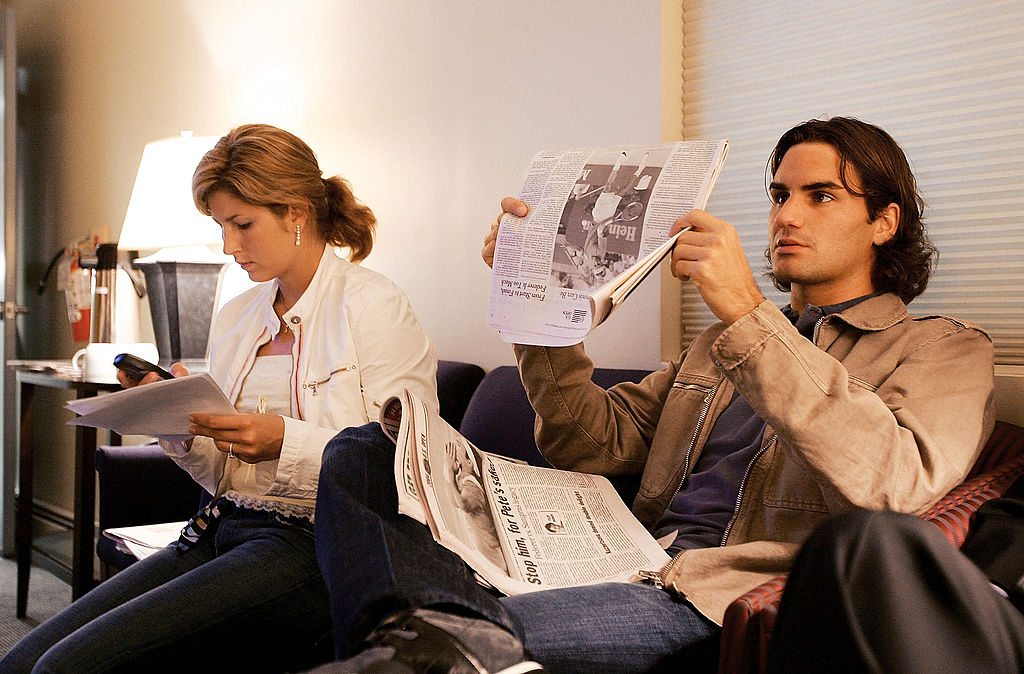 NEW YORK - SEPTEMBER 13: Roger Federer of Switzerland reads the newspapers while his girlfriend Mirka Vavrinec works the phone before Federer's apparence on the CBS Early Show on September 13, 2004 in New York City. Federer defeated Lleyton Hewitt of Australia yesterday to win the US Open and his third Grand Slam title of the year. (Photo by Ezra Shaw/Getty Images)