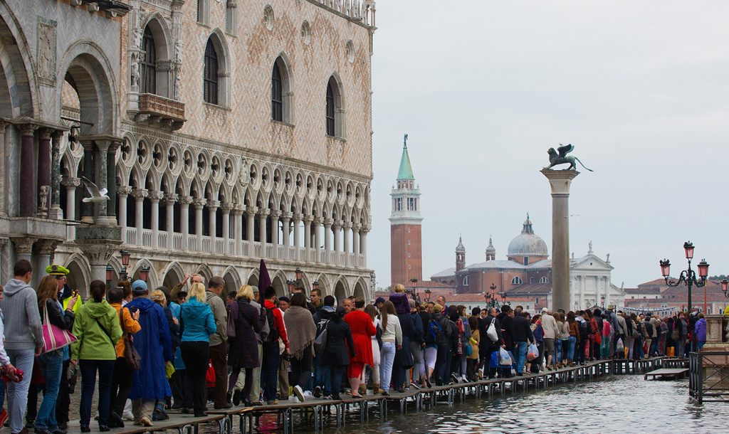 VENICE, ITALY - OCTOBER 07: Tourists and Venetians stand on walkways during the first "Acqua Alta" of the season on October 7, 2013 in Venice, Italy. The high tide, or acqua alta as it is locally known, is a natural event most commonly affecting the city during Autumn and Winter. (Photo by Marco Secchi/Getty Images)