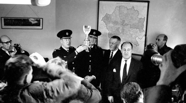 A police officer shows off the Jules Rimet trophy to the assembled press after it was discovered in a suburban street by a small dog called Pickles